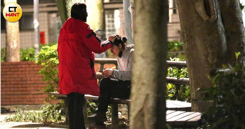 坐在公園的椅子上，李威抽著電子菸，女伴撫摸著他的頭髮。（圖／本刊攝影組）